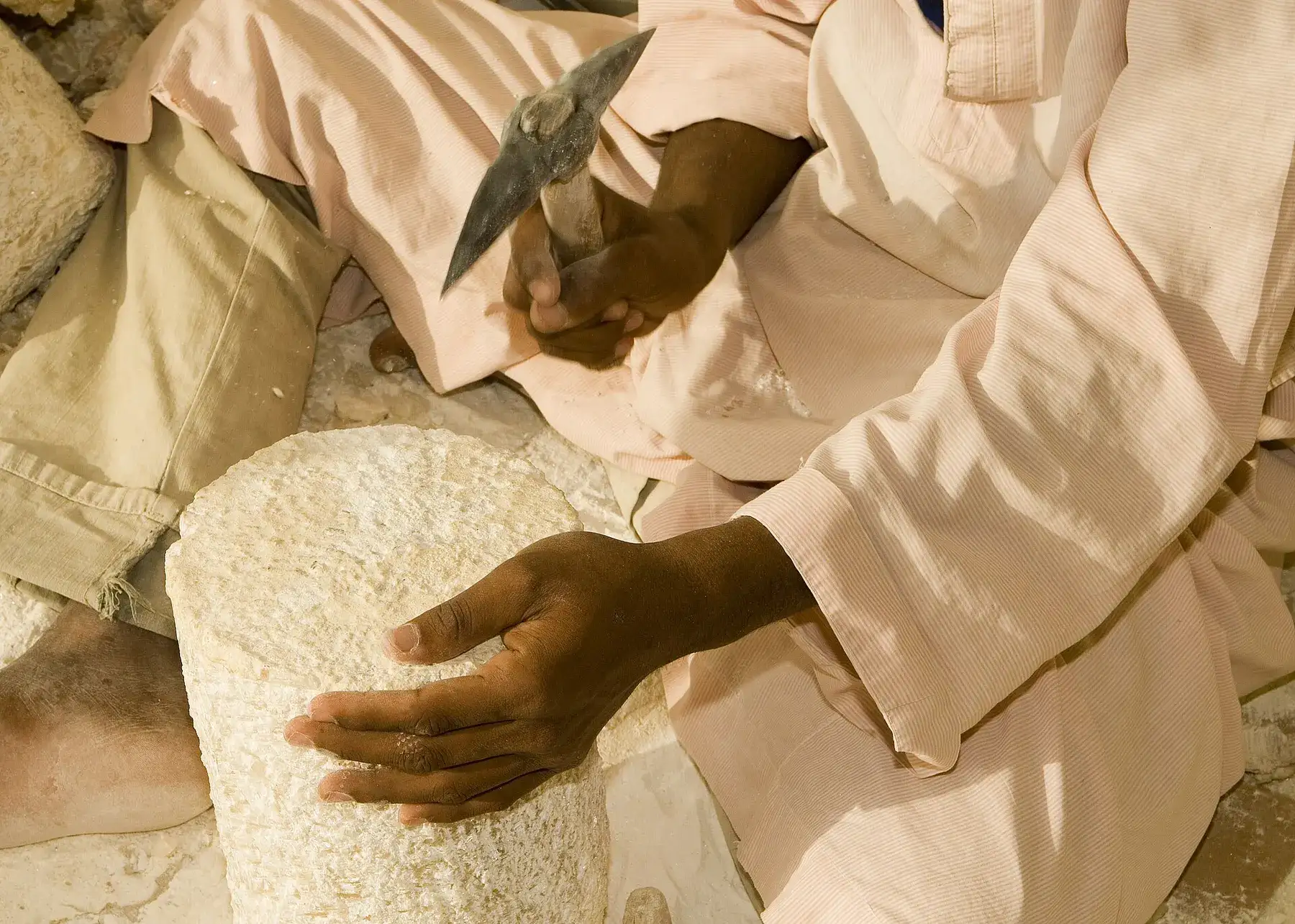 A worker in Luxor shaping a block of alabaster by hand with a chisel, in a photograph from 2007.