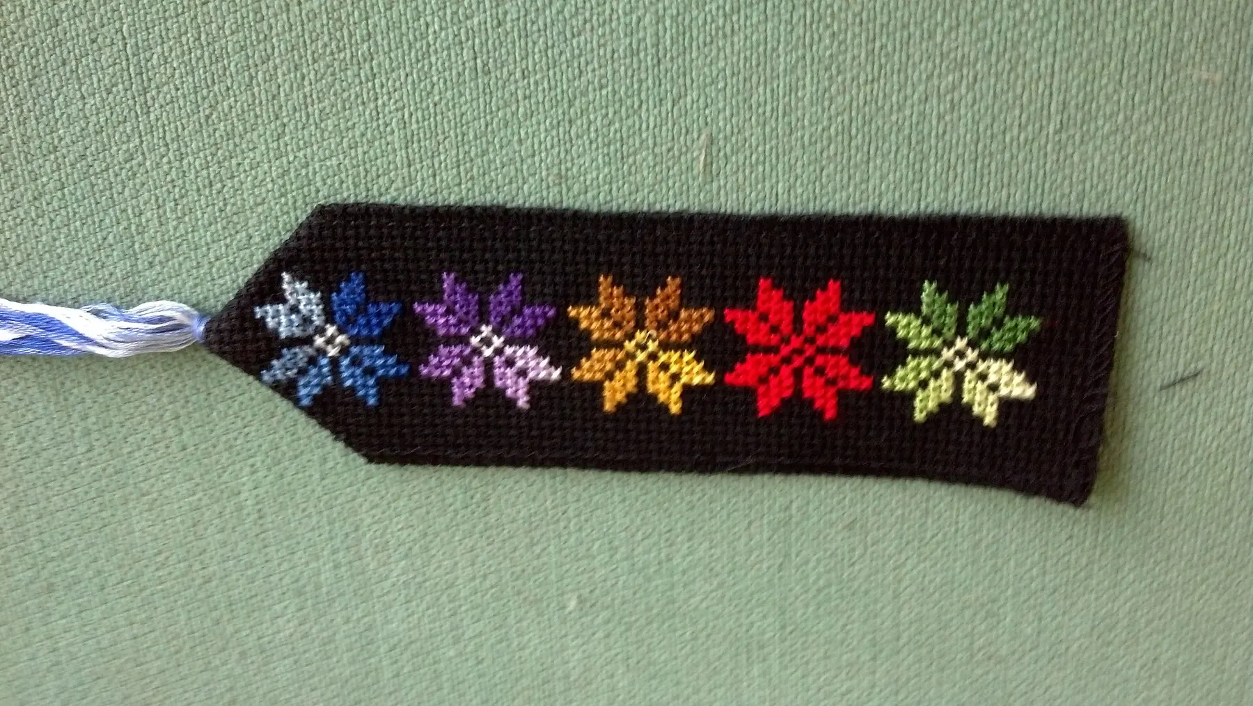 Bedouin cross-stitch stars in coloured thread on a black fabric bookmark; where it was made is not recorded.