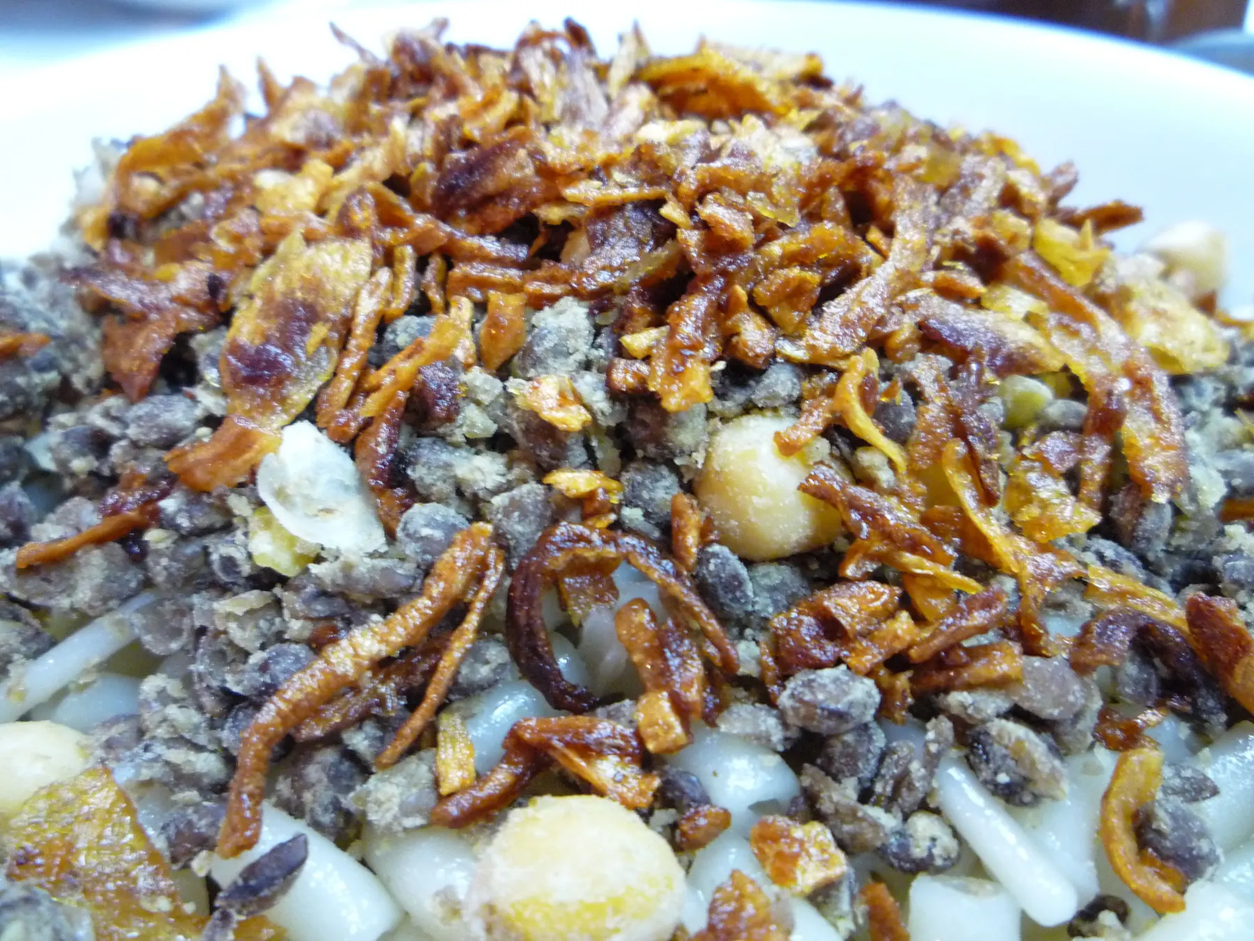 A plate of koshari in Cairo: rice, lentils and pasta topped with crisp fried onions and chickpeas.