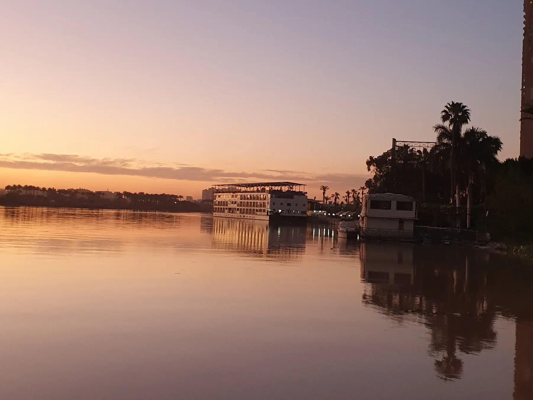 The Nile at Maadi, Cairo, at sunset, with a moored river boat reflected in still water.