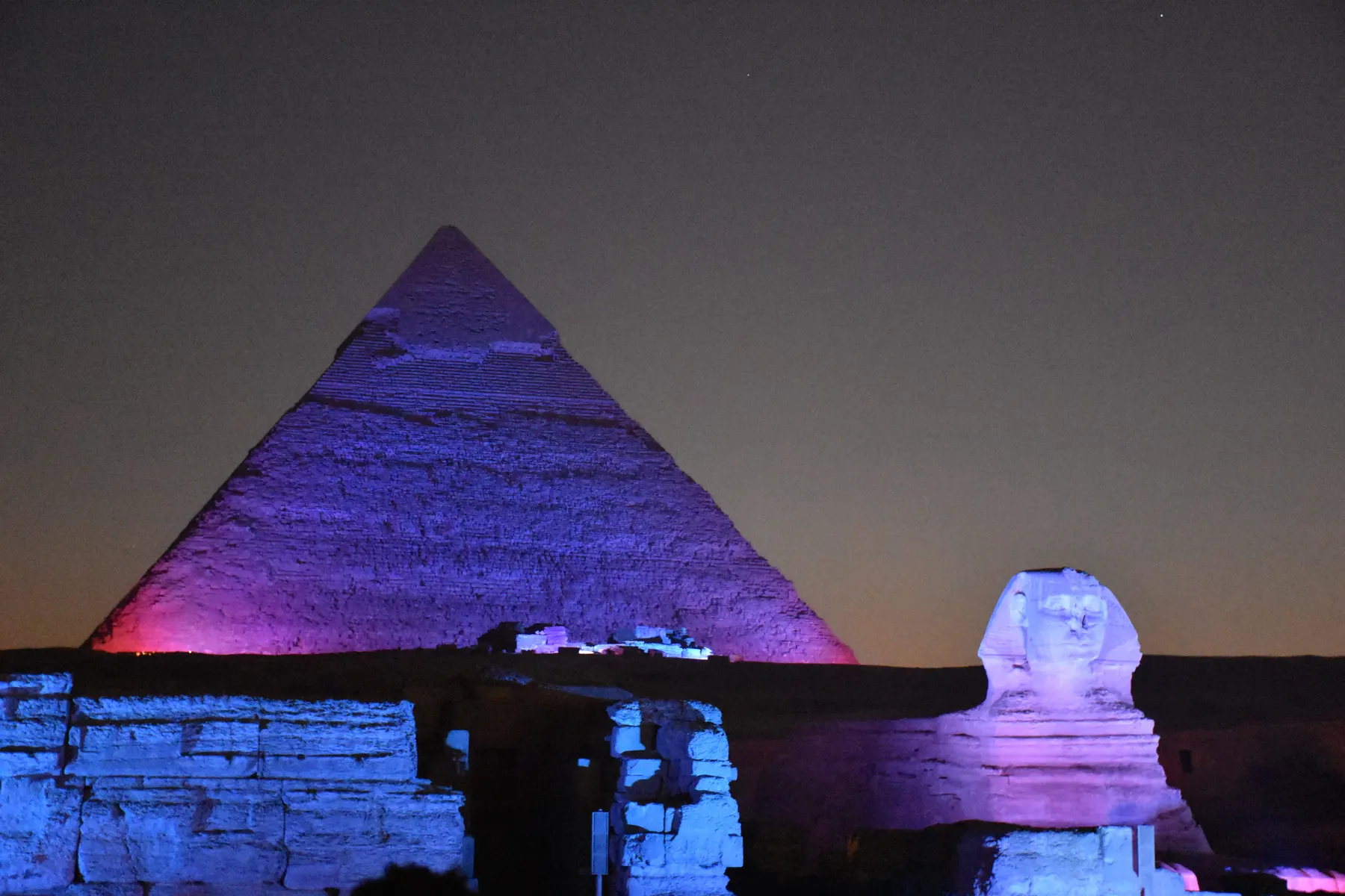 The Pyramid of Khafre and the Sphinx lit in purple and blue during the Sound and Light show at Giza.