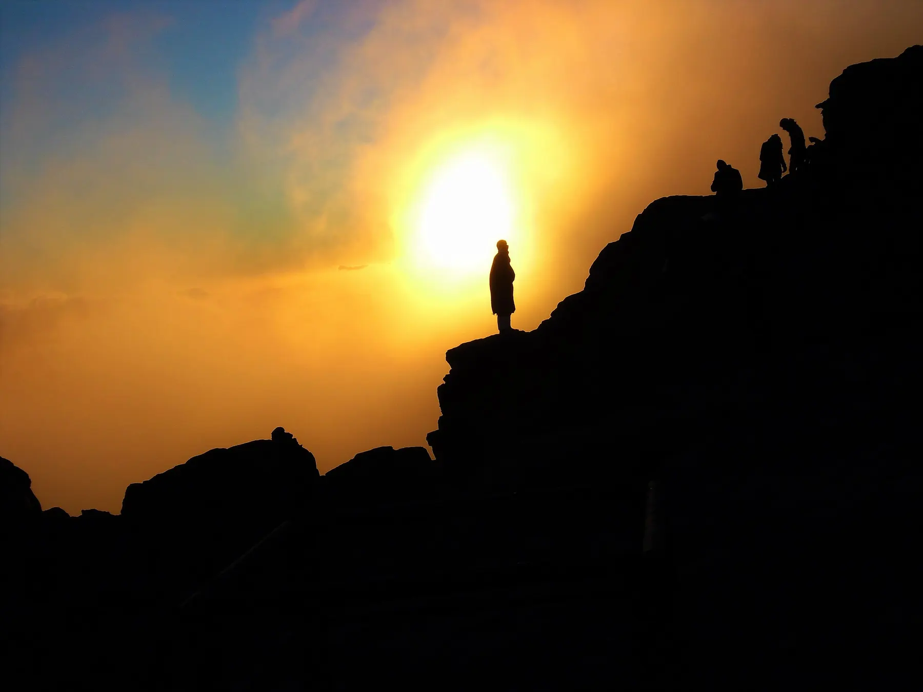 Walkers silhouetted on the rocks at the summit of Mount Sinai as the sun rises.