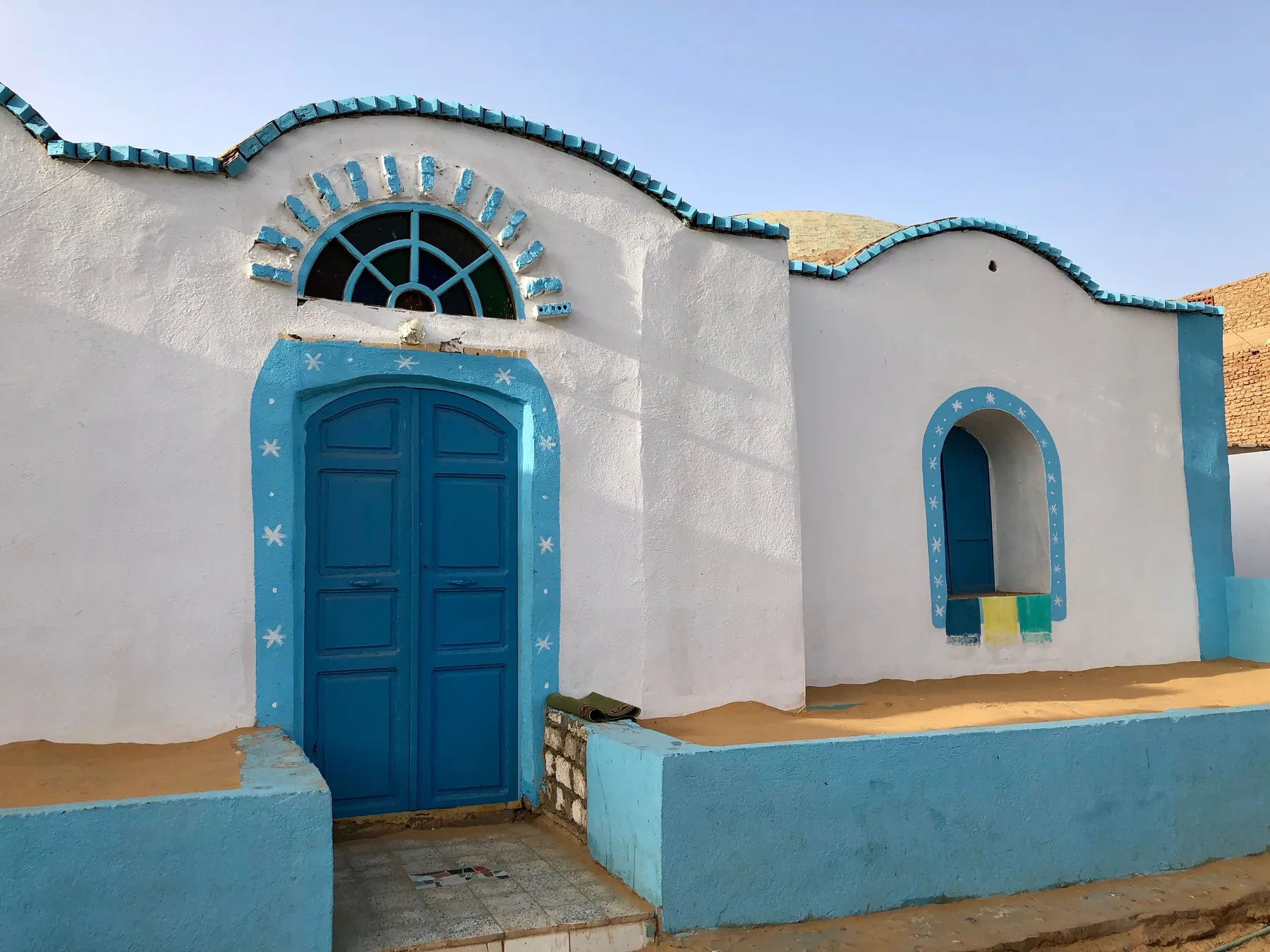A white Nubian house with a blue painted door and patterned trim at Gharb Soheil, near Aswan.