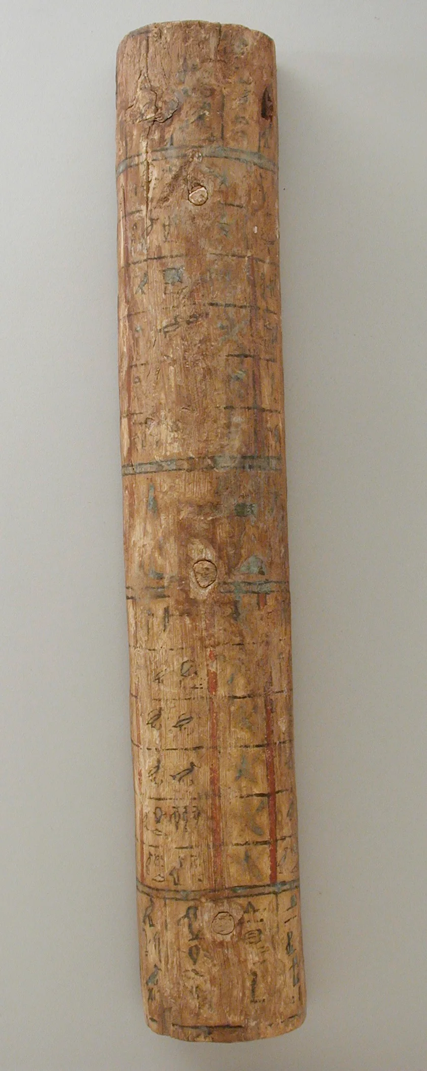 A narrow strip of painted wood from a coffin lid, with a grid of cells, signs in some of them and blue-grey bands across it.