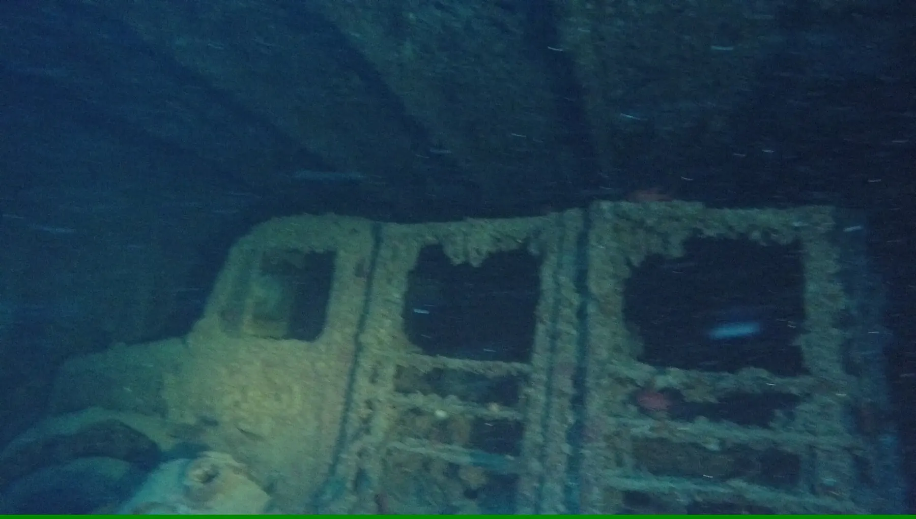 A truck in a cargo hold of the Thistlegorm wreck, its cab covered in marine growth.