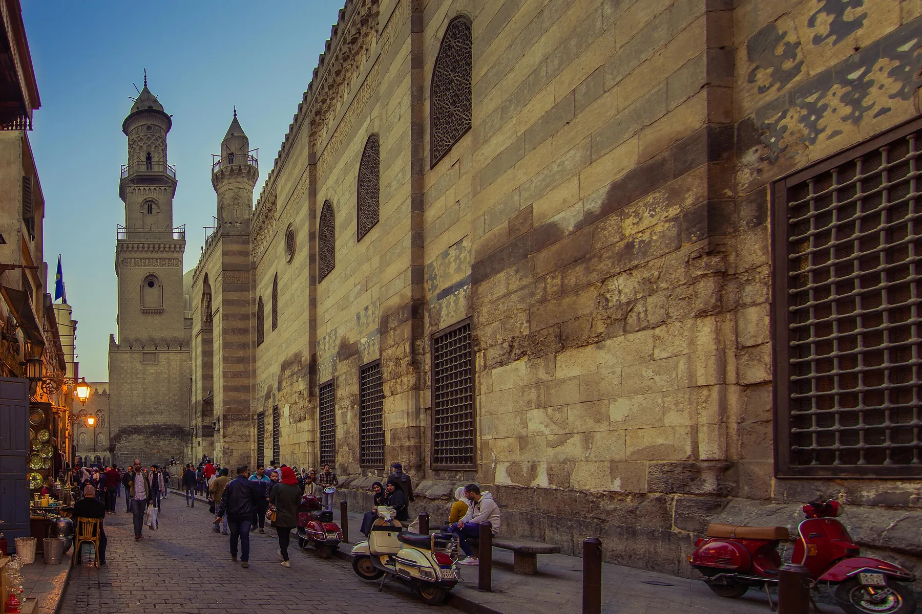 Al-Mu'izz Street looking towards the minarets of the Qalawun and Barquq complexes, past a long Mamluk facade.