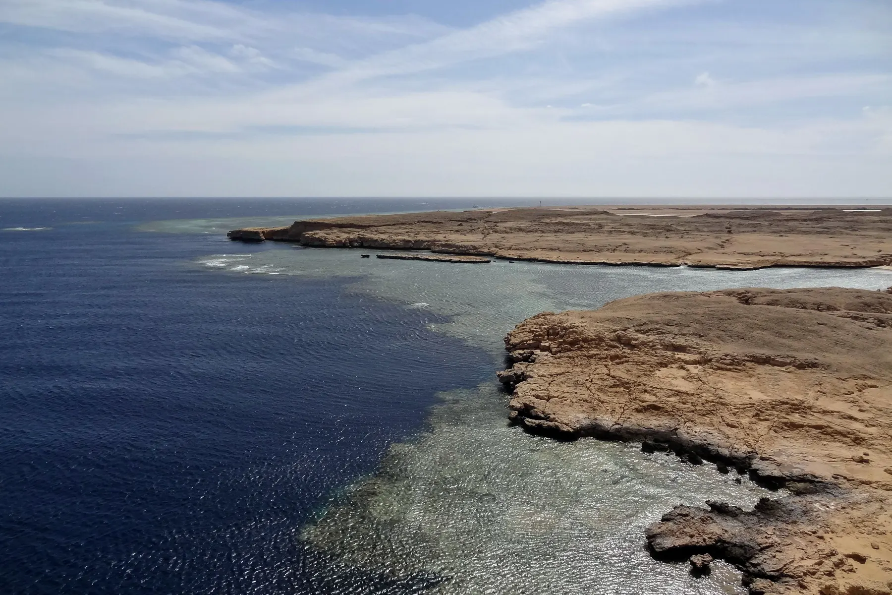 The coral reef edge at Ras Mohammed National Park, where shallow reef meets deep blue water below the Sinai cliffs.
